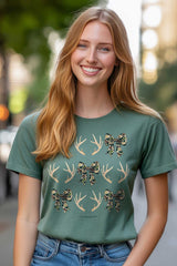 Woman wearing a green t-shirt with antler and bow design on a blurred city street background