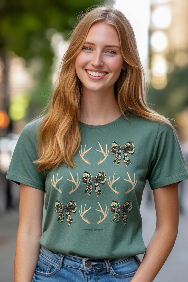 Woman wearing a green t-shirt with antler and bow design on a blurred city street background