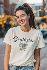 Woman wearing a 'Southern' t-shirt with a bow graphic on a city street.