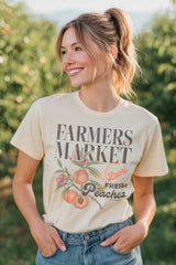 Woman wearing a 'Farmers Market Fresh Peaches' t-shirt in an orchard.