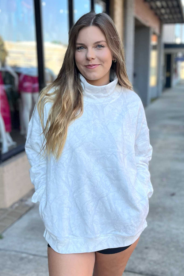 Woman wearing a white sweatshirt and black shorts on a sidewalk.