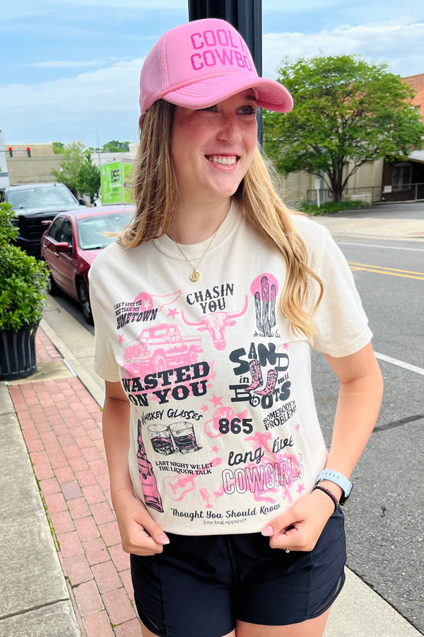 Person wearing a pink cap and graphic t-shirt on a sidewalk