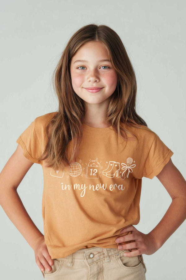 Young girl wearing a mustard yellow t-shirt with text on a plain background