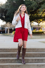 Woman in a red dress and brown boots walking up steps outdoors.