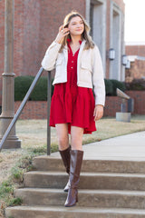 Woman in a red dress and white cardigan walking up steps outdoors.