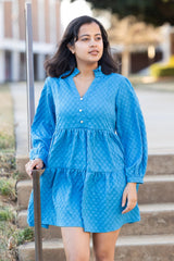 Woman in a blue dress standing outdoors on steps