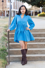 Woman in a blue dress and brown boots standing on steps outdoors
