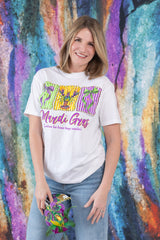 Woman wearing a white t-shirt with colorful graphics and text, standing in front of a vibrant, abstract wall.