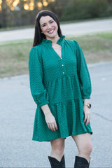 Woman wearing a green dress standing outdoors with a blurred background