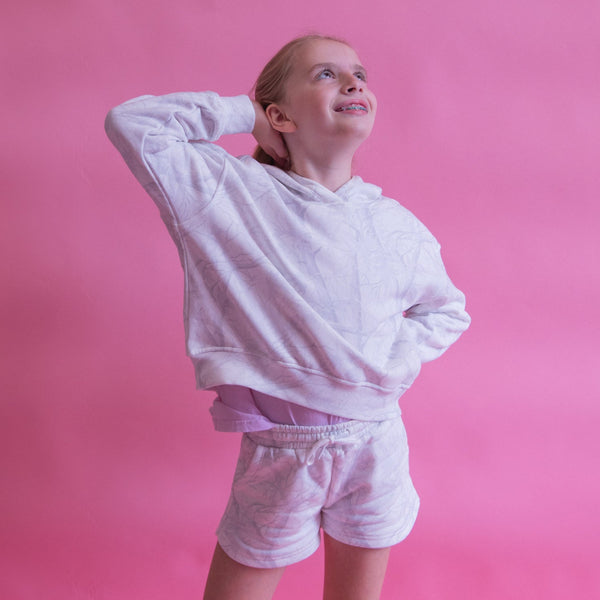 Young girl in a white sweatsuit against a pink background