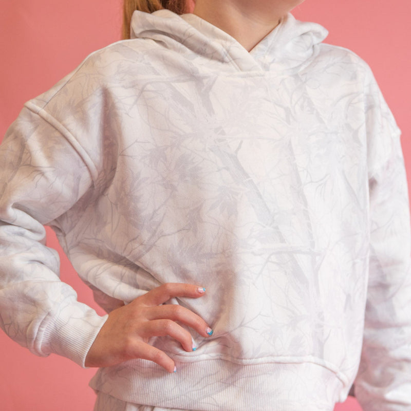 Person wearing a white hoodie against a pink background